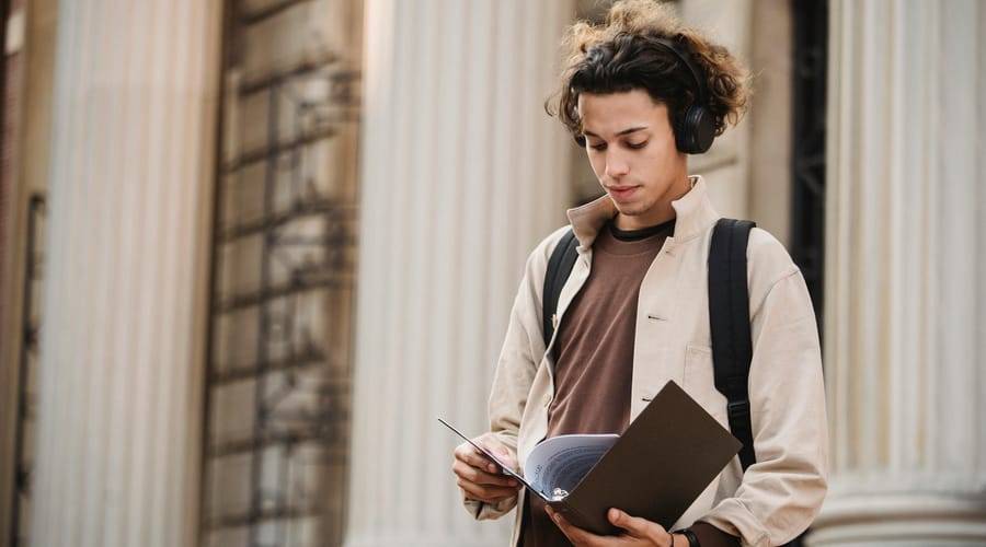 Chico con papeles en las manos, estudiando en un curso de inglés intensivo.