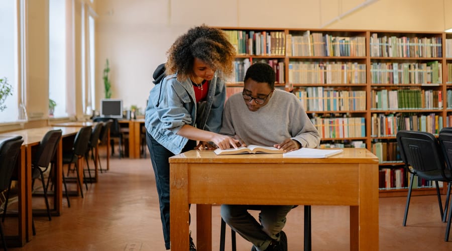 Dos jóvenes comparten un diccionario inglés - español en una sesión de aprendizaje de idiomas.