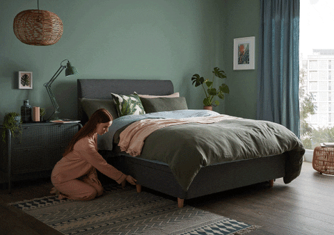 una mujer en su habitación sacando una almohada del cajón de la cama