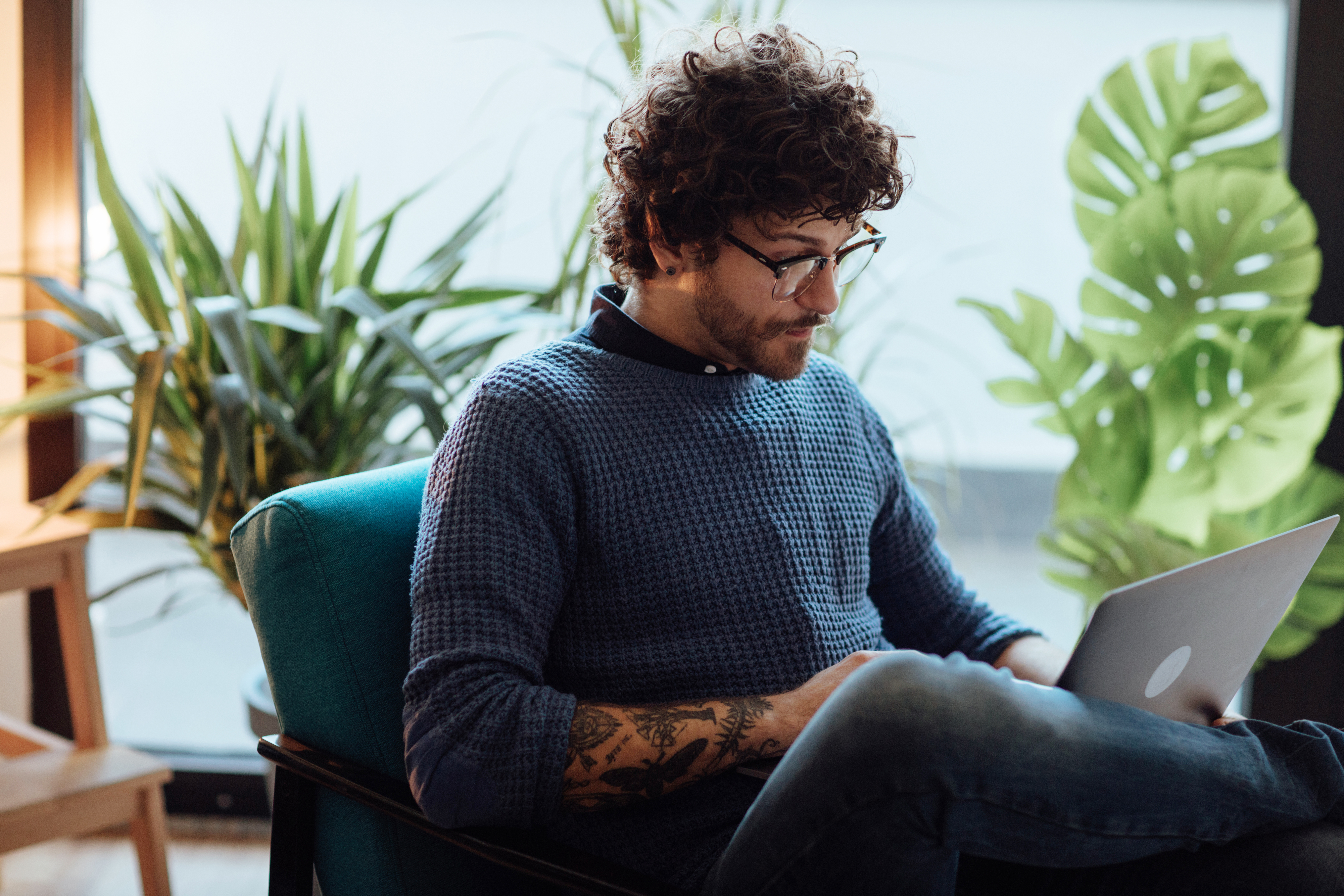 Hombre sentado en un sillón estudiando en su computadora